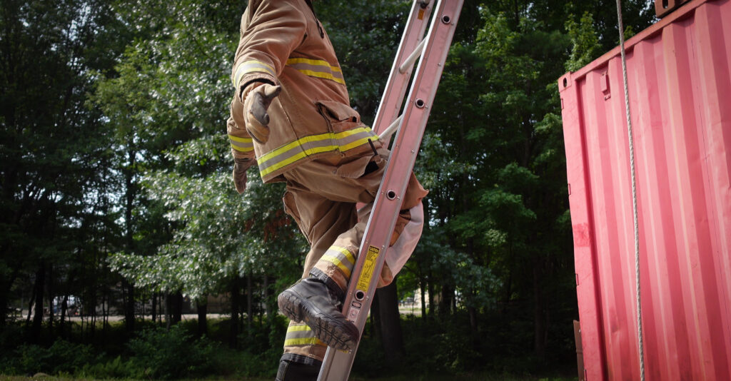 A firefighter demonstrating a completed leg lock maneuver on an extension ladder.