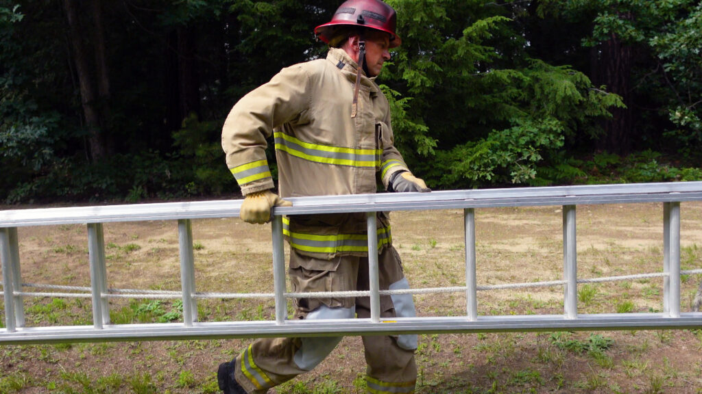 A firefighter carrying an extension ladder like a suitcase.