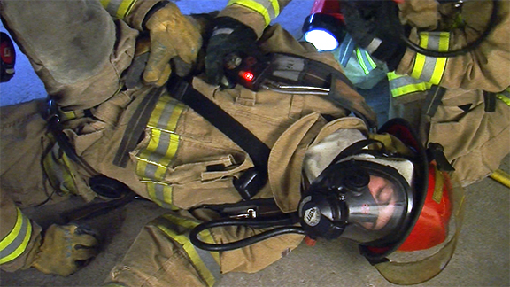 Two firefighters assess a down team member